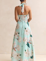 Mint green floral dress with a halter neck and tied straps on a beige background