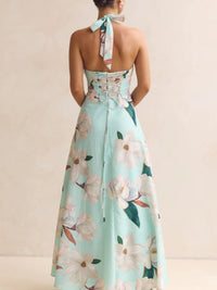 Mint green floral dress with a halter neck and tied straps on a beige background