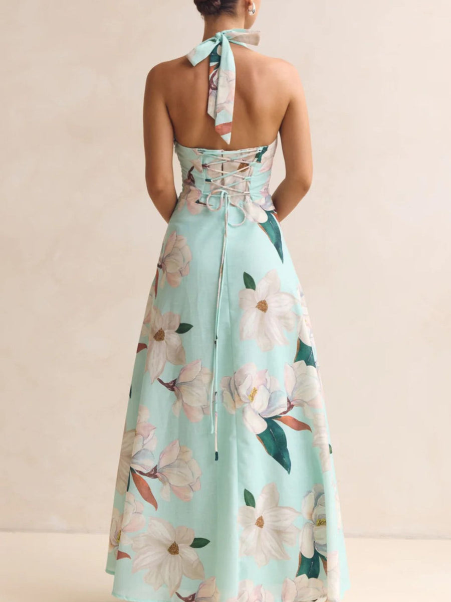 Mint green floral dress with a halter neck and tied straps on a beige background