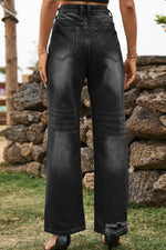 Person wearing black wide-leg jeans standing in front of a stone wall.