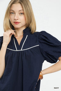 Woman wearing a navy blue dress with white trim on a white background