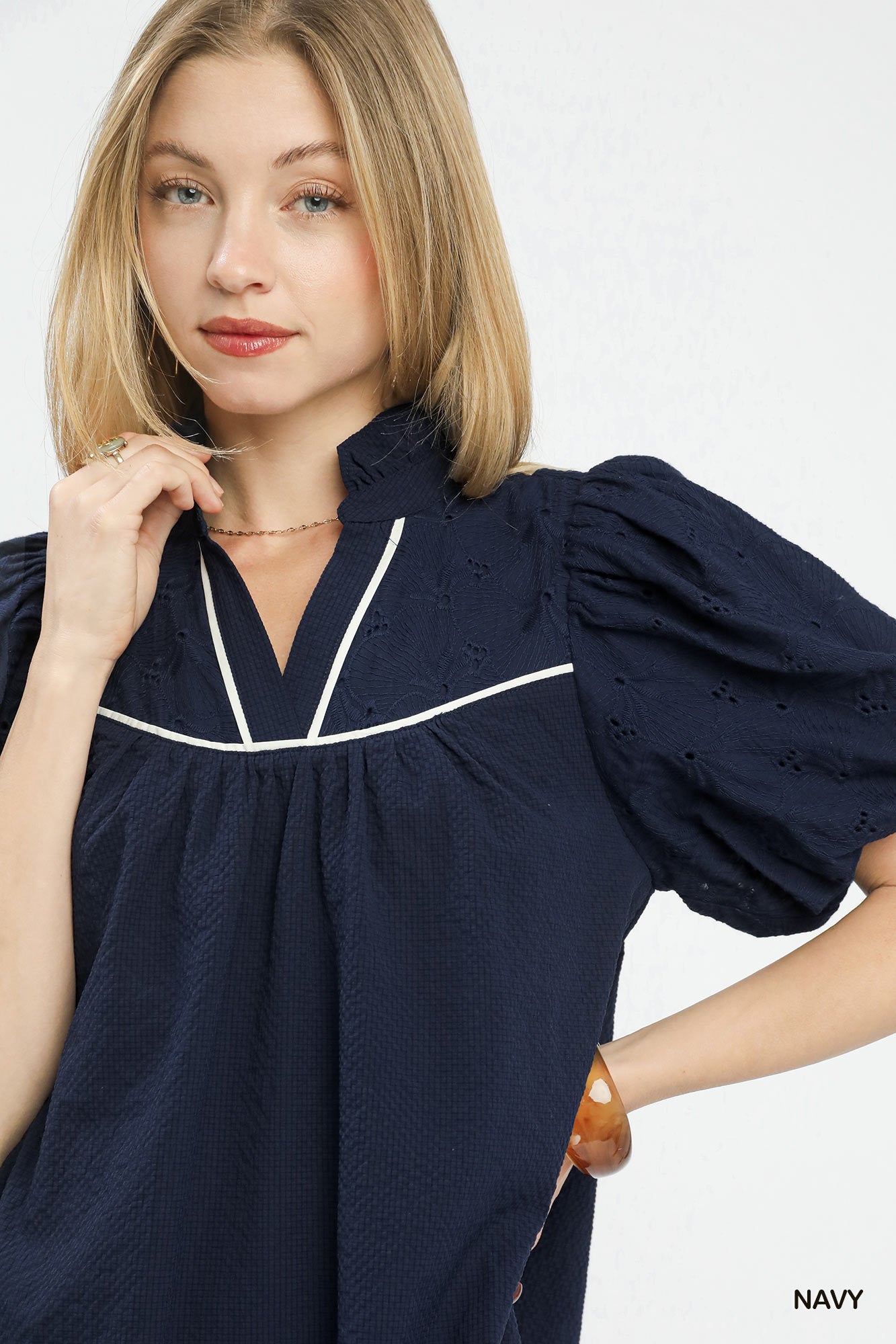 Woman wearing a navy blue dress with white trim on a white background