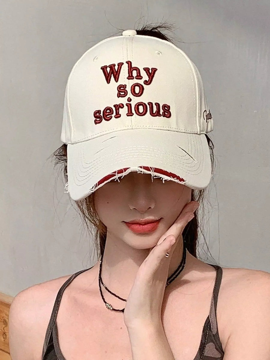 Person wearing a beige cap with 'Why so serious' text against a plain background