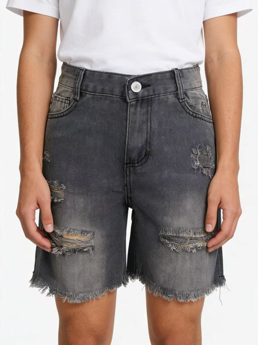 Person wearing distressed gray denim shorts on a white background
