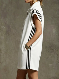 White sleeveless dress with black stripes worn by a person against a gray background