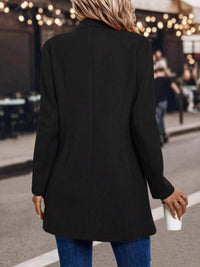 Person wearing a black coat walking on a street with blurred background