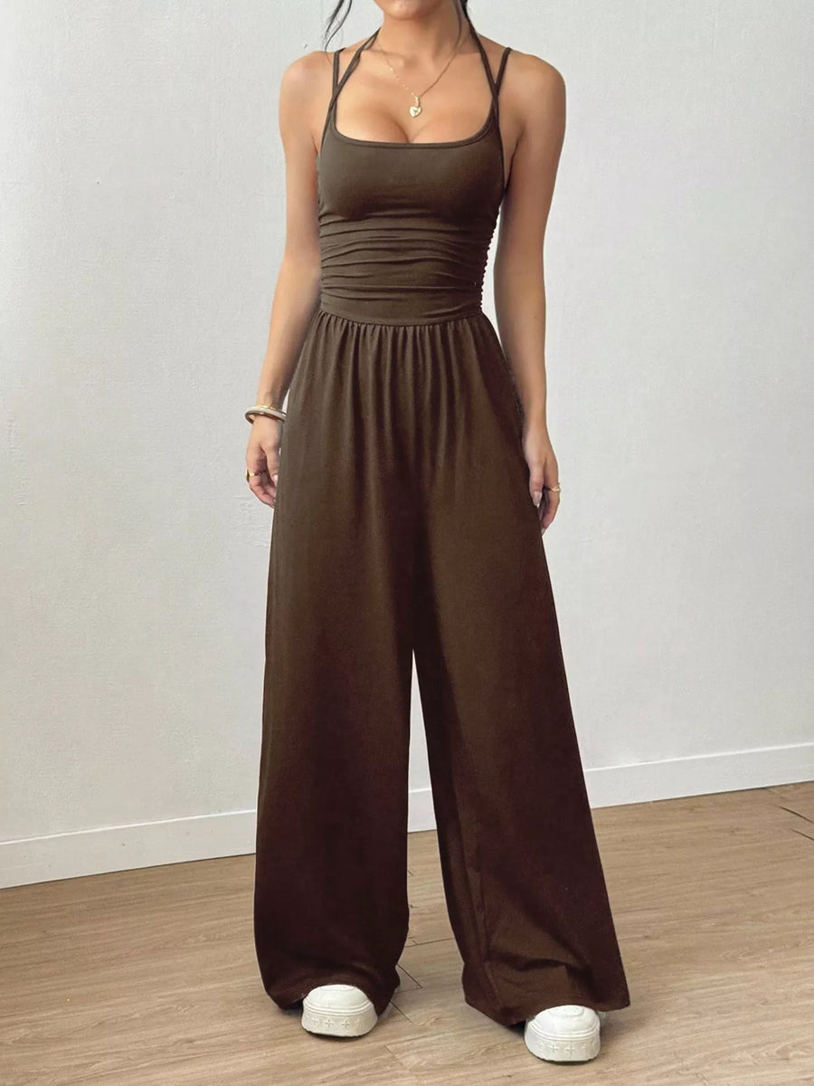 Woman wearing a burgundy jumpsuit on a plain background