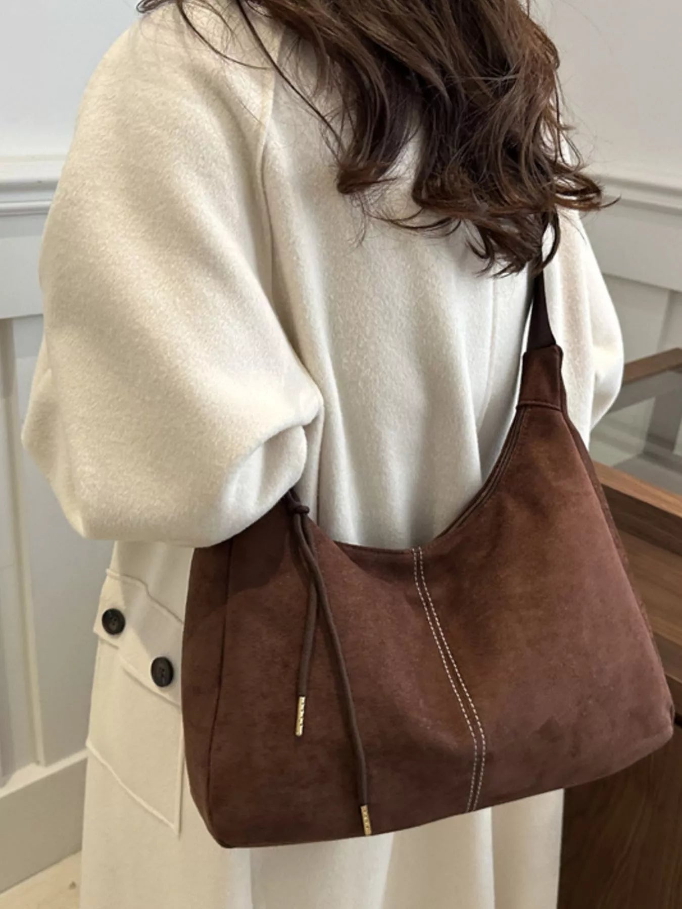 Person wearing a brown shoulder bag indoors