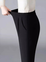 Black pants being adjusted on a plain background