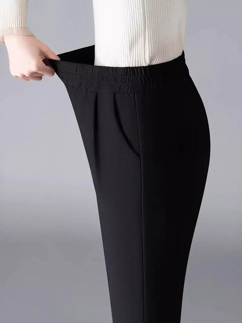 Black pants being adjusted on a plain background