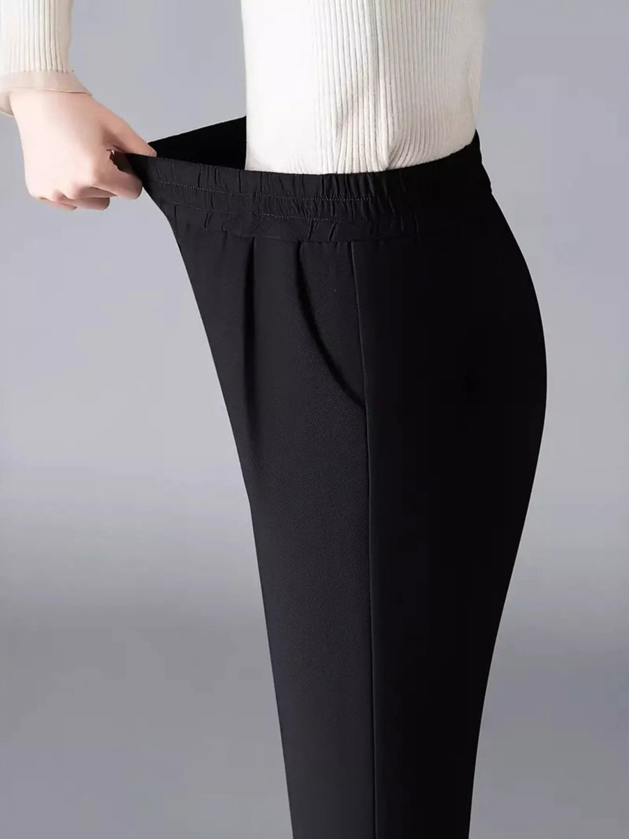 Black pants being adjusted on a plain background