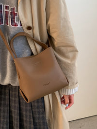 Person holding a brown handbag with a neutral background
