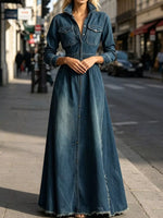 A woman wearing a long-sleeve, button-front denim maxi dress with a collar and frayed hem, standing on a city street.