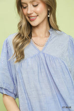 Woman wearing a light blue blouse with a green background