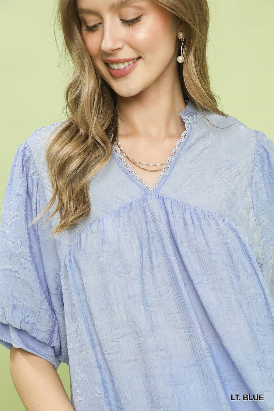 Woman wearing a light blue blouse with a green background