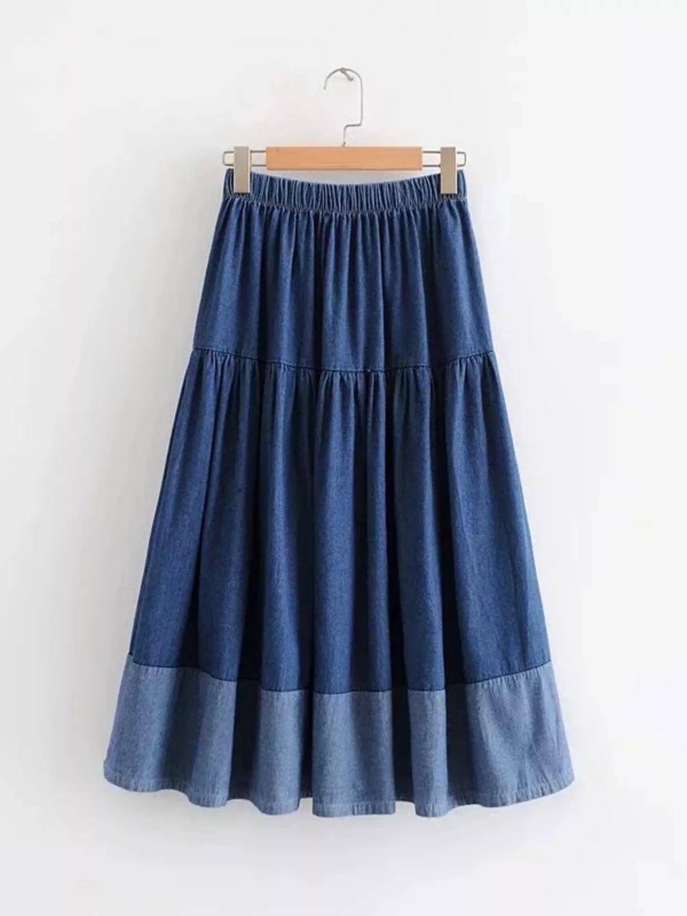 Blue denim skirt on a hanger against a white background