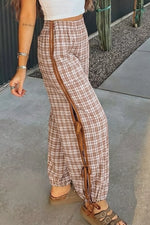 Person wearing plaid pants with a brown stripe on a sidewalk.