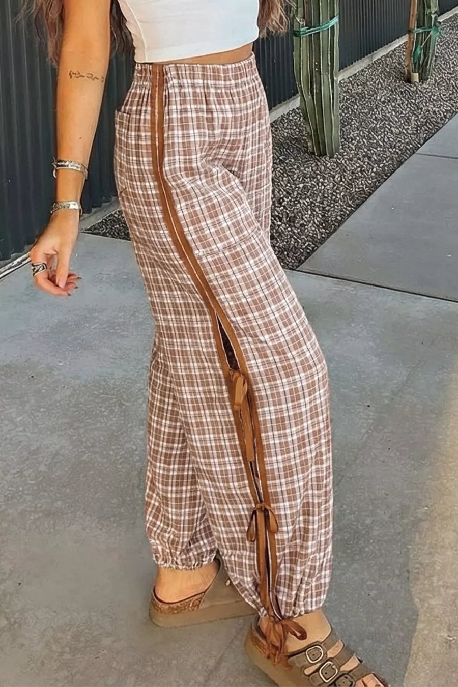 Person wearing plaid pants with a brown stripe on a sidewalk.
