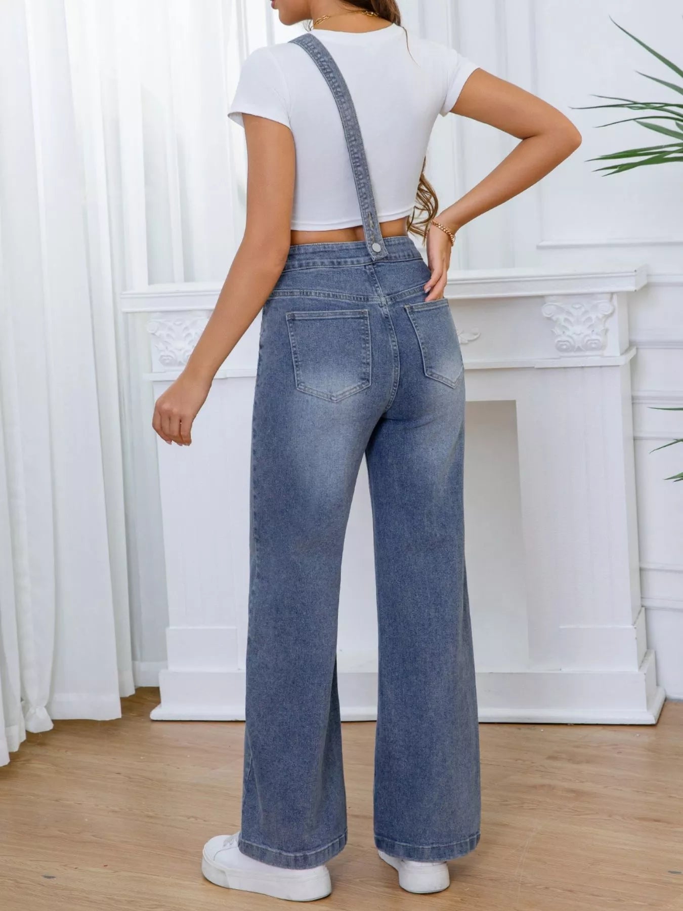 Person wearing blue denim overalls with a white background