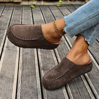 Brown suede loafers worn on a wooden floor