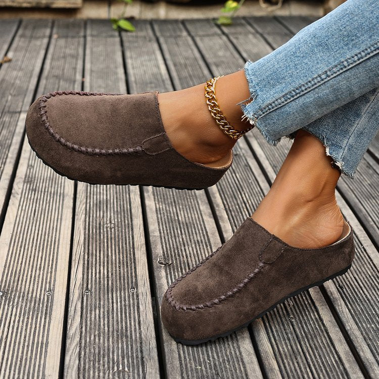 Brown suede loafers worn on a wooden floor