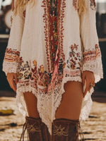 Person wearing a bohemian-style dress with intricate patterns and brown boots on a blurred background