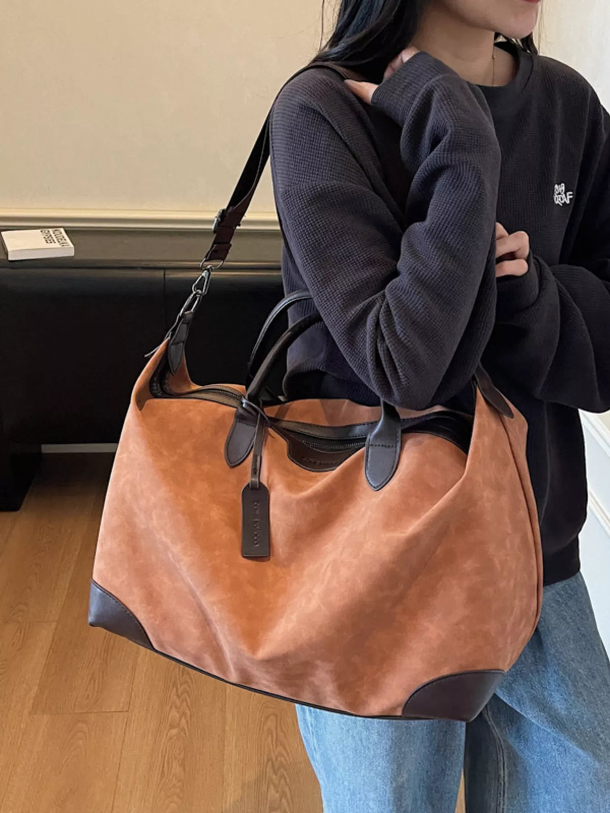 Person holding a brown leather handbag with a blurred background