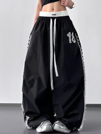 Black wide-leg pants with white accents and numbers on a plain background