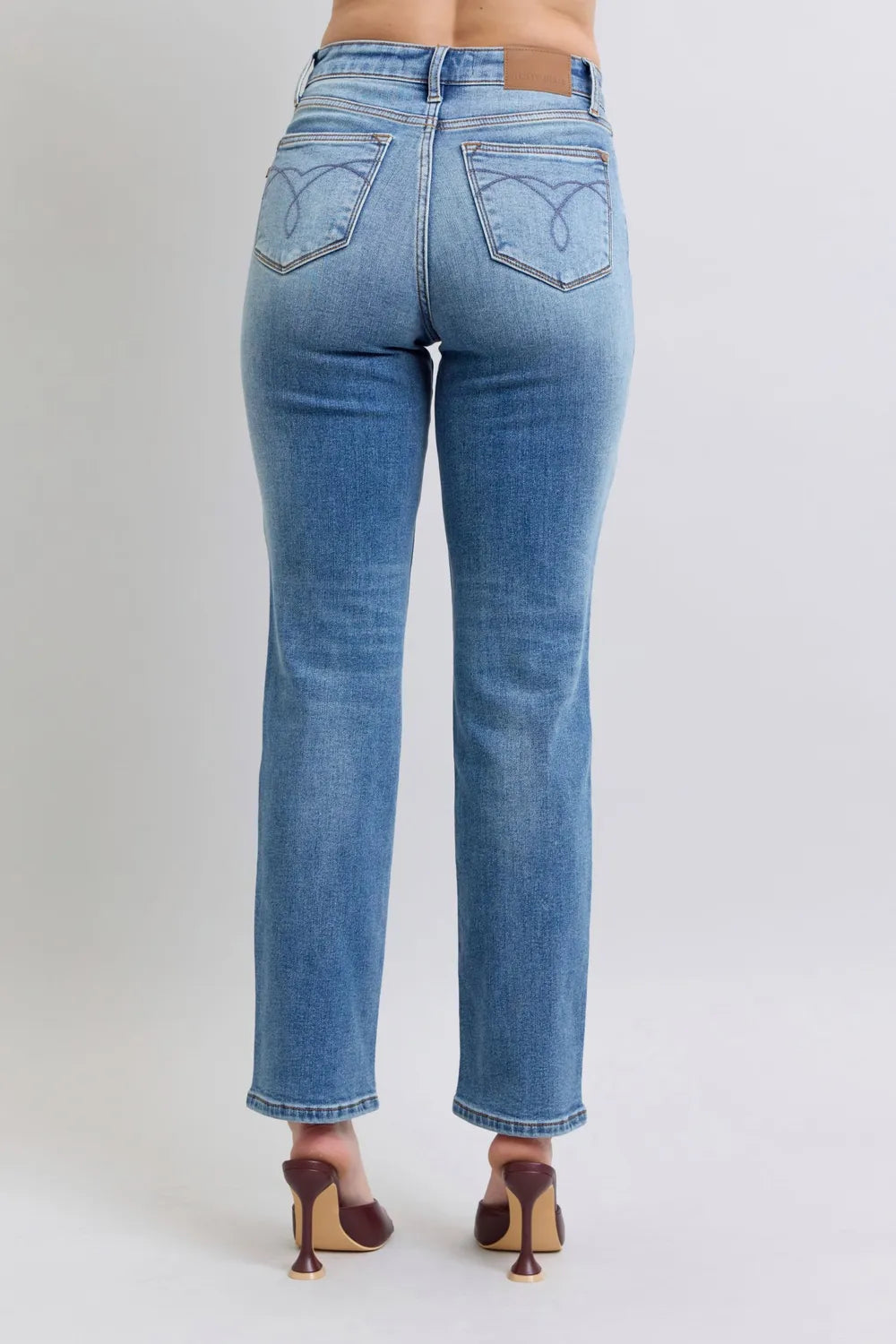 Blue jeans worn by a person on a plain background