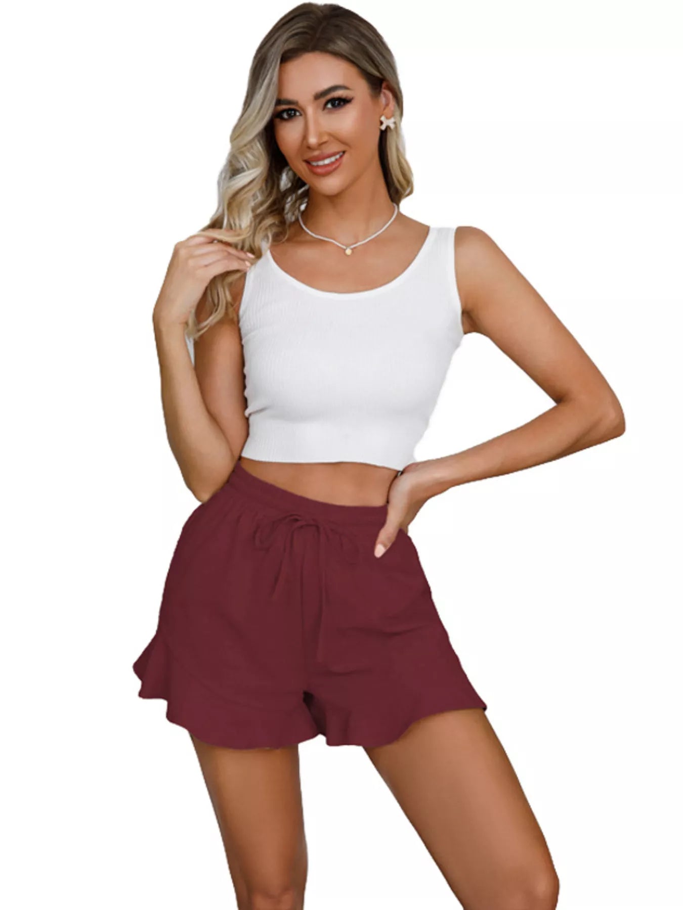 Woman wearing a white sleeveless top and maroon shorts on a white background