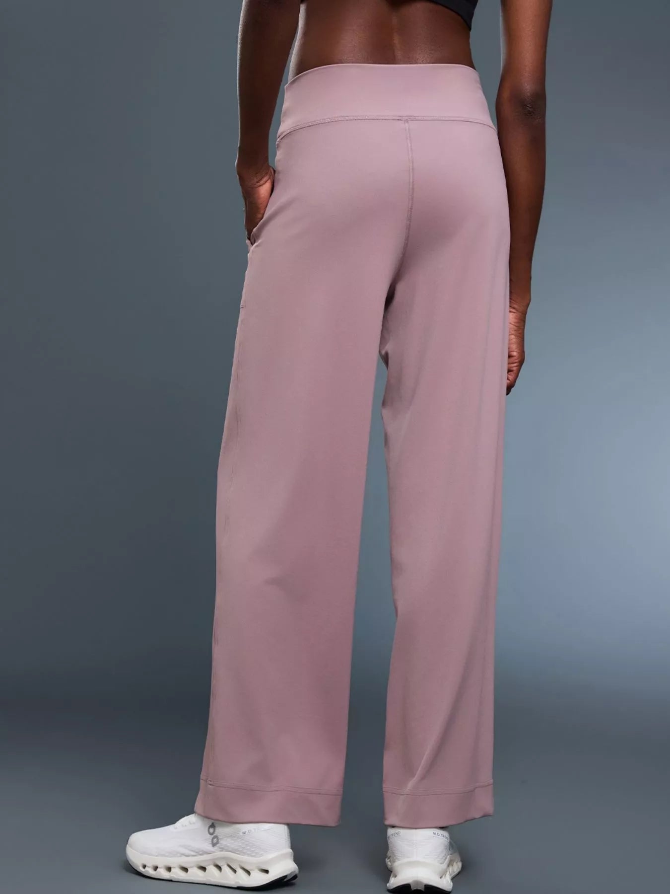 Person wearing pink wide-leg pants on a gray background