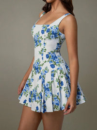 Woman wearing a white dress with blue floral pattern against a neutral background