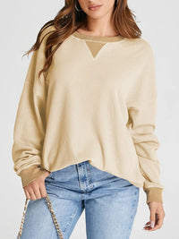 Woman wearing a beige sweater and blue jeans on a white background