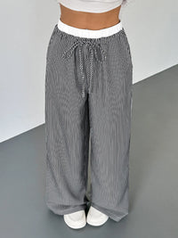Striped pants worn by a person on a gray floor with a white background