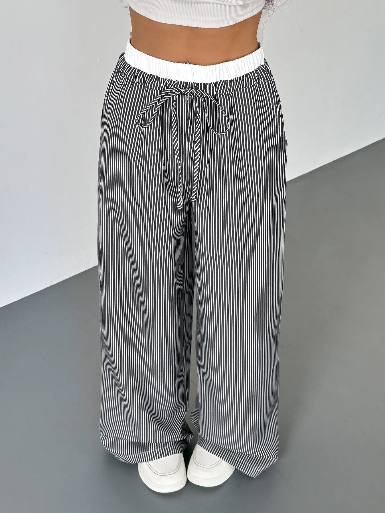 Striped pants worn by a person on a gray floor with a white background