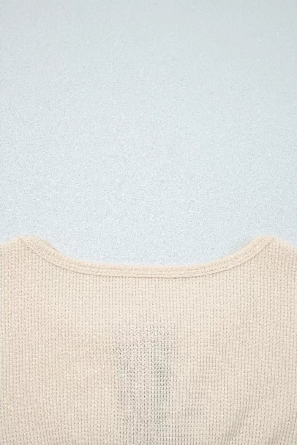 Close-up of a beige textured garment on a light blue background