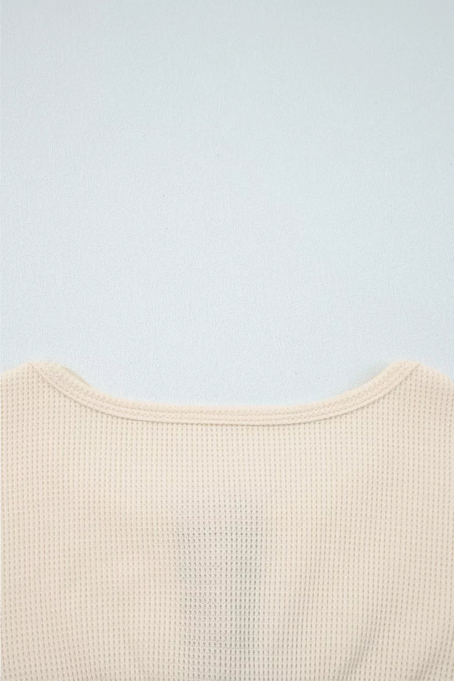 Close-up of a beige textured garment on a light blue background