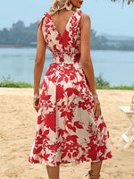 Woman wearing a red and white floral dress on a beach.