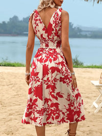 Woman wearing a red and white floral dress on a beach.