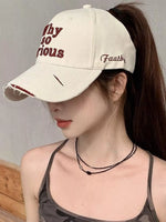 Person wearing a beige cap with text, against a neutral background