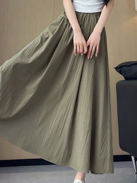 Person wearing a long olive green skirt in an indoor setting