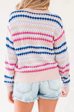 A woman shown from the back wearing a pastel striped crochet sweater with pink, blue, and white horizontal stripes, paired with light-wash denim shorts.