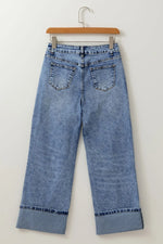 Blue jeans on a hanger against a white background
