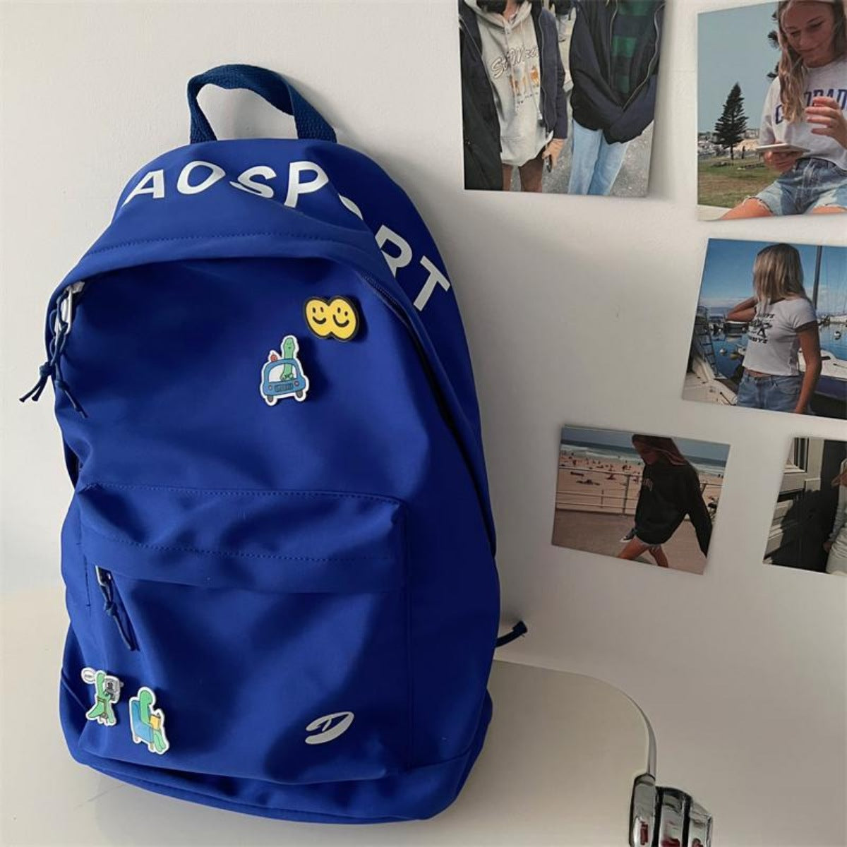 Blue backpack with patches on a white surface with photos in the background
