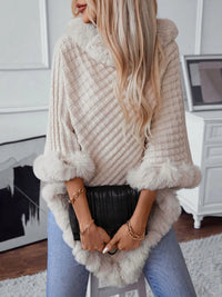 Woman wearing a fluffy beige cardigan with fur trim in a room.