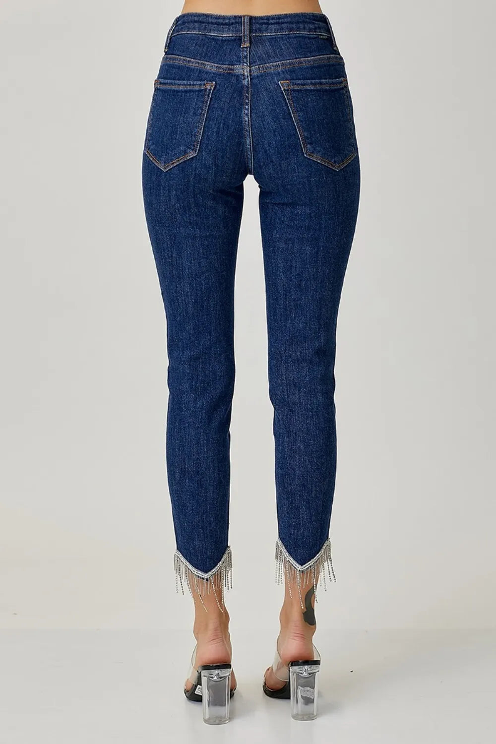 Blue jeans with fringe details on a white background