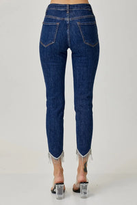 Blue jeans with fringe details on a white background