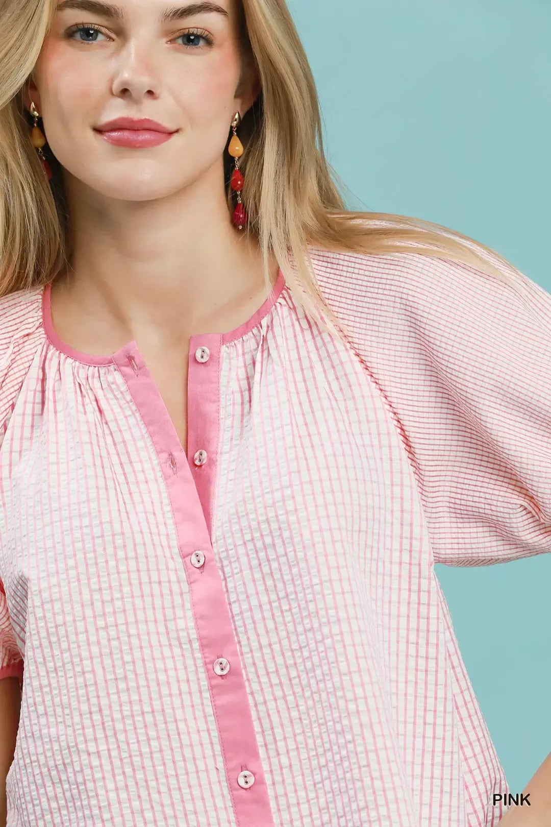 Woman wearing a pink and white checkered blouse with a blue background