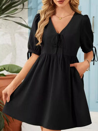 Woman wearing a black dress with puffed sleeves in an indoor setting.