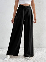 Person wearing black wide-leg pants and a white top against a white background